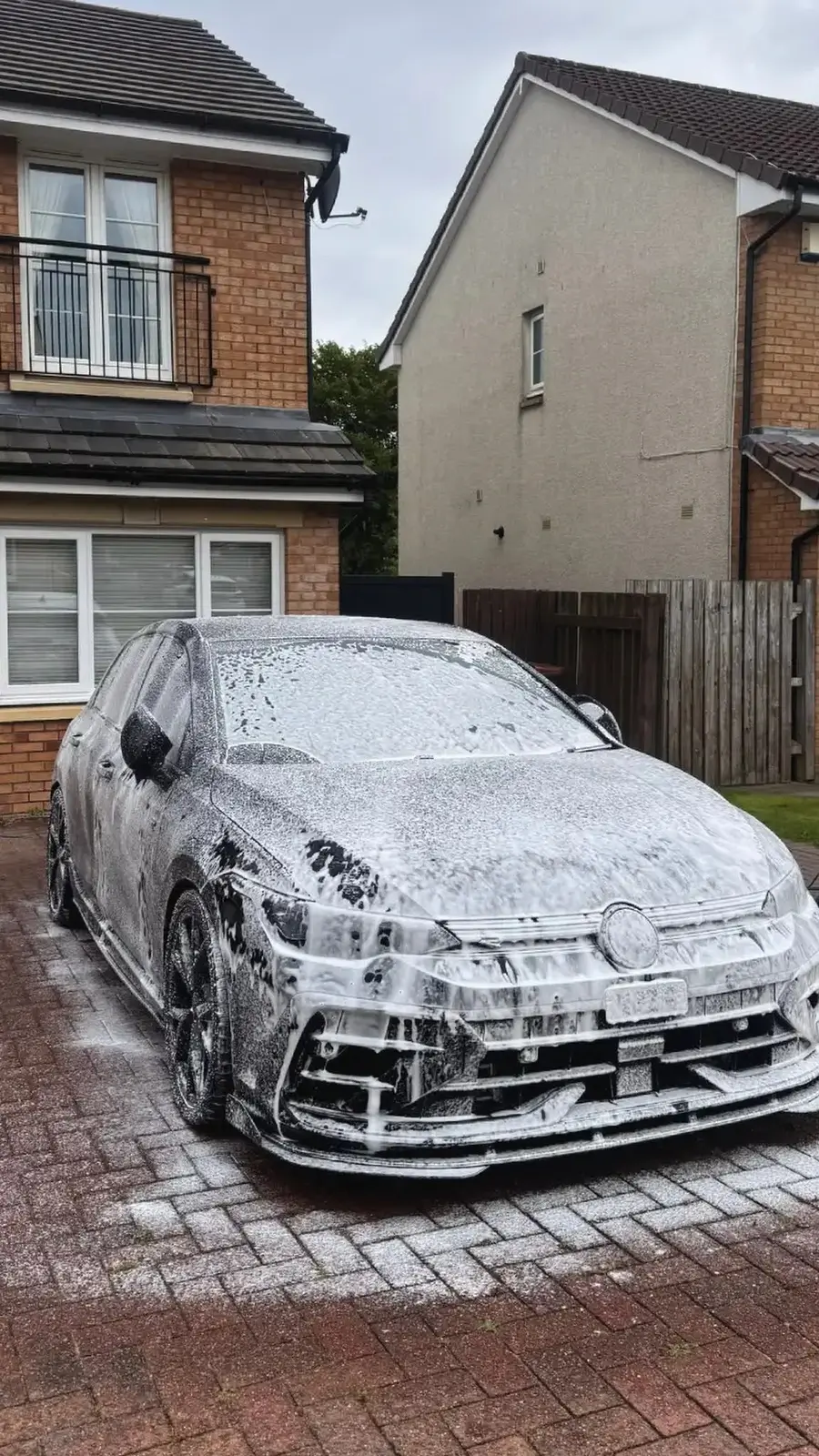 Black Volkswagen Golf R covered in snow foam during the pre-wash stage